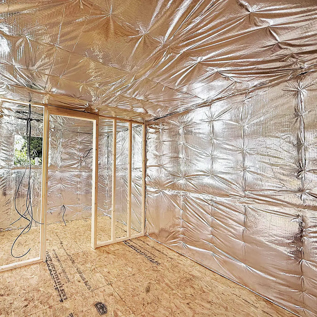 Multi-layer foil insulation installed on walls and ceiling of a timber-framed room, reflecting heat to improve energy efficiency and indoor warmth.